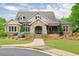 Beautiful home exterior with a stone facade, a covered porch, and a manicured lawn at 134 Johnston Farm Ln, Woodstock, GA 30188
