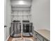 Modern laundry room featuring stainless steel washer and dryer, wire shelves, and gray cabinetry at 2180 Oakpointe Ct, Buford, GA 30519