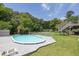 A backyard pool with wooden deck is fenced-in and surrounded by green grass and mature trees at 2180 Oakpointe Ct, Buford, GA 30519