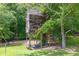 An elevated treehouse sits among the trees on a sunny day in the backyard at 2180 Oakpointe Ct, Buford, GA 30519