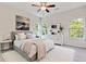 Bright bedroom featuring a ceiling fan, large bed, white dresser and windows overlooking the lush green yard at 70 Wheeler Lake Path, Dallas, GA 30157