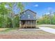 Two story house exterior with new driveway, a wooden porch and mature trees in the back at 70 Wheeler Lake Path, Dallas, GA 30157