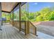 Side porch with wood decking and rails provides outdoor enjoyment and complements the home's exterior, set against a wooded backdrop at 70 Wheeler Lake Path, Dallas, GA 30157