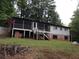 View of back exterior with a screened porch and brick foundation, surrounded by trees and a sloped yard at 135 Golden Hills Dr, Woodstock, GA 30189