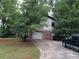 Home exterior with attached garage, driveway, brick accents, siding, and surrounding trees at 135 Golden Hills Dr, Woodstock, GA 30189
