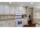 Kitchen features white cabinets, granite counters, stainless appliances, hardwood floors and nearby laundry at 2191 Flowering Dr, Grayson, GA 30017