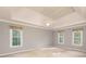 Spacious bedroom with tray ceiling, neutral paint, and three large windows at 386 Collegiate Dr, Powder Springs, GA 30127