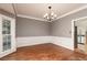 This dining room has hardwood floors, a chandelier, wainscoting, a large window, and light gray walls at 386 Collegiate Dr, Powder Springs, GA 30127