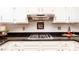 Close up of a kitchen stovetop with custom backsplash and white cabinets at 386 Collegiate Dr, Powder Springs, GA 30127