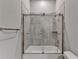 Modern bathroom with a glass-enclosed tub and shower and stylish marble-look tile at 3925 Sierra Knolls Ct, Cumming, GA 30040
