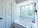 Well-lit bathroom showcasing a deep soaking tub and natural light from a window at 1215 Smoke Hill Ln, Hoschton, GA 30548