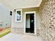 Covered front porch featuring a gray brick facade, entrance door, and small window at 4495 Buttonwood Ln, Lilburn, GA 30047