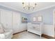 A light blue Bedroom featuring a white crib and closet with wall decor and a large window at 220 Foxley Way, Roswell, GA 30075