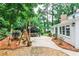 A charming patio features a dining area under a pergola and a wooden swing surrounded by lush greenery at 2244 Deer Ridge Dr, Tucker, GA 30087
