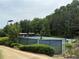 A view of the community's fenced tennis court with lights, seating, and beautiful tree surroundings at 2244 Deer Ridge Dr, Tucker, GA 30087