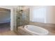 Bathroom with glass-enclosed shower and standalone tub, accented by neutral tiling and natural light at 5015 Montes Ln, Cumming, GA 30040