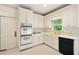 Kitchen with white cabinetry, double ovens, black dishwasher, and a bright yellow sink at 1256 Spring Park Sw Dr, Atlanta, GA 30311