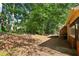 A view of the backyard covered in pinestraw and some wooded area near the edge of the property and a section of the house at 373 Dixie Ct, Lawrenceville, GA 30046