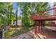 Spacious backyard with tall trees, a red deck, and a brick patio, offering a serene outdoor space at 1224 Everwood Sw Dr, Marietta, GA 30008