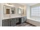 Bright bathroom featuring double sinks, gray cabinetry, and a soaking tub next to a window at 1224 Everwood Sw Dr, Marietta, GA 30008