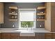 Well-lit kitchen with floating shelves, custom cabinets, stainless steel dishwasher and farmhouse style sink at 1285 Stuart Rdg, Johns Creek, GA 30022