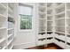 Bright walk-in closet featuring custom shelving, drawers, and a window providing natural light at 1285 Stuart Rdg, Johns Creek, GA 30022