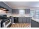 Kitchen featuring gray cabinets, a modern black gas range and oven, stainless sink and wood-look flooring at 12237 Cypress Ln, Fayetteville, GA 30215