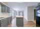 Well-lit kitchen with gray cabinets, light countertops, stainless steel sink, and a view into the adjacent living room at 12237 Cypress Ln, Fayetteville, GA 30215