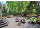 Outdoor patio with wood chairs, gas grill, fire pit, and dining table surrounded by lush greenery offers an idyllic backyard setting at 1435 Withmere Ln, Atlanta, GA 30338