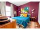 Stylish bedroom with plum walls, vibrant bedding, wooden floors and abstract artwork at 1608 Carroll Nw Dr, Atlanta, GA 30318
