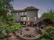 Evening view of expansive backyard with a stone patio, outdoor kitchen, fire pit, and lush landscaping at 3282 Green Farm Trl, Dacula, GA 30019