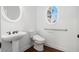 Clean, bright bathroom with a modern pedestal sink, sleek fixtures, and an oval window at 448 Hanover Drive, Villa Rica, GA 30180