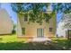 View of the home's backyard featuring a small patio, green grass, partial fence, and mature shade trees at 4812 Browns Mill Ferry Rd, Lithonia, GA 30038