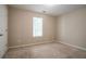 Serene bedroom with a carpeted floor, a bright window, and a door, bathed in neutral tones at 4812 Browns Mill Ferry Rd, Lithonia, GA 30038