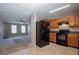 Open concept kitchen with black appliances and wooden cabinets overlooks a bright and open living room at 4812 Browns Mill Ferry Rd, Lithonia, GA 30038