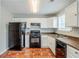 Functional kitchen with black appliances, white cabinets, and tiled floor at 4889 Hidden Creek Pl, Decatur, GA 30035