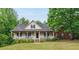 Charming home with a covered front porch, green lawn, and mature trees around the property at 418 Whisper Wood Way, Locust Grove, GA 30248