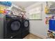 Convenient laundry room with modern black washer and dryer, shelving and a window for natural light at 418 Whisper Wood Way, Locust Grove, GA 30248