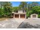 Charming two-story home boasts a two car garage and separate additional garage, surrounded by lush trees and a generous driveway at 466 Victoria Rd, Woodstock, GA 30189