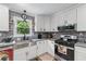 Charming kitchen features stainless sink, stone backsplash, modern appliances, and white custom cabinets at 466 Victoria Rd, Woodstock, GA 30189