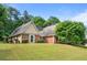 Charming single-story home featuring a brick and tan siding exterior with a well-maintained lawn and mature trees at 221 The Esplanade Se Way, Loganville, GA 30052