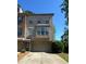 Attractive multi-story brick townhome with manicured lawn, driveway, and mature trees in the background at 288 Blue Pointe Ct, Suwanee, GA 30024