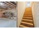 Spacious unfinished basement with exposed ceiling beams and wooden stairs, offering potential for customization at 1010 Capella Creek Way, Grayson, GA 30017