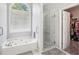 Bright bathroom featuring a soaking tub, glass shower, and walk-in closet at 1010 Capella Creek Way, Grayson, GA 30017