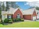 Exterior view of the brick home showcasing lush green lawn, shrubbery and two-car garage at 1010 Capella Creek Way, Grayson, GA 30017