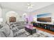 View of living room featuring a gray sectional sofa, hardwood floors, ceiling fan and a large TV at 1010 Capella Creek Way, Grayson, GA 30017