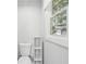 Clean, neutral bathroom with a white toilet, shelving unit, and a bright window at 1712 Shirley Sw St, Atlanta, GA 30310