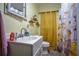 Bright bathroom with a decorative mirror, floating shelves, and a toilet next to a shower with vibrant curtains at 8053 Duralee Ln, Douglasville, GA 30134