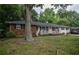 Single-story home features a brick facade, a covered front porch, and a large tree in the front yard, offering shade and curb appeal at 8053 Duralee Ln, Douglasville, GA 30134