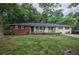 Charming single-story home with a brick accent and welcoming front porch, surrounded by mature trees and a lush green lawn at 8053 Duralee Ln, Douglasville, GA 30134
